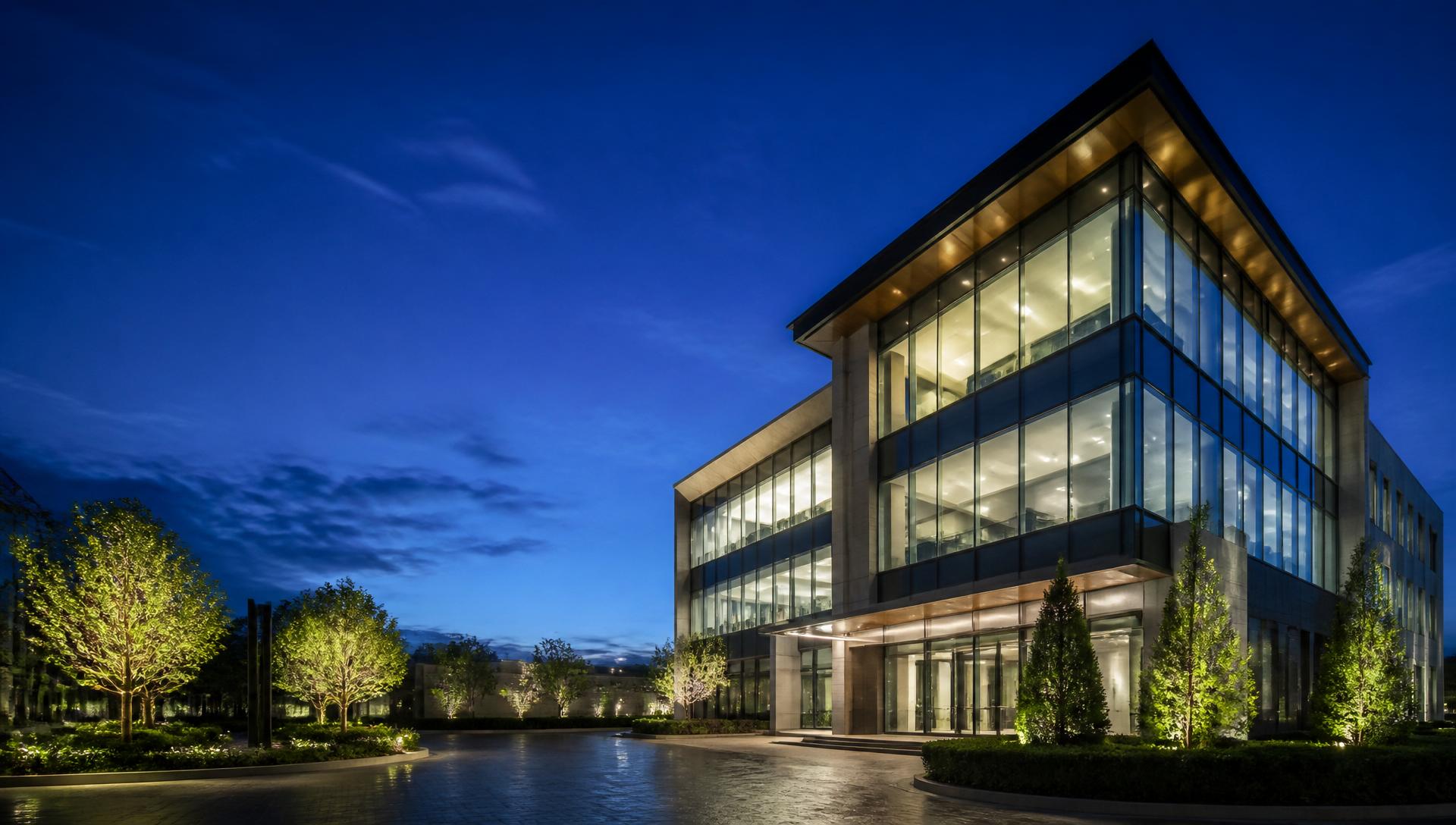 Modern illuminated commercial office building at blue hour, representing the quality of Seacorals projects